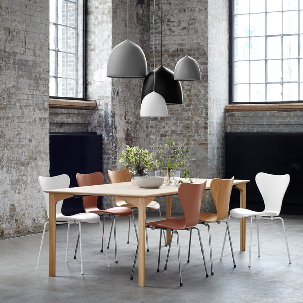 The Suspence Pendant Light by Fritz Hansen in different colors and sizes above a dining chair
